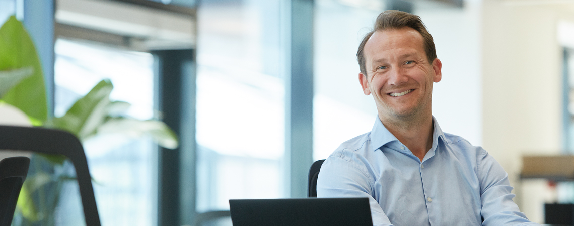 Smilende mand ved sit skrivebord