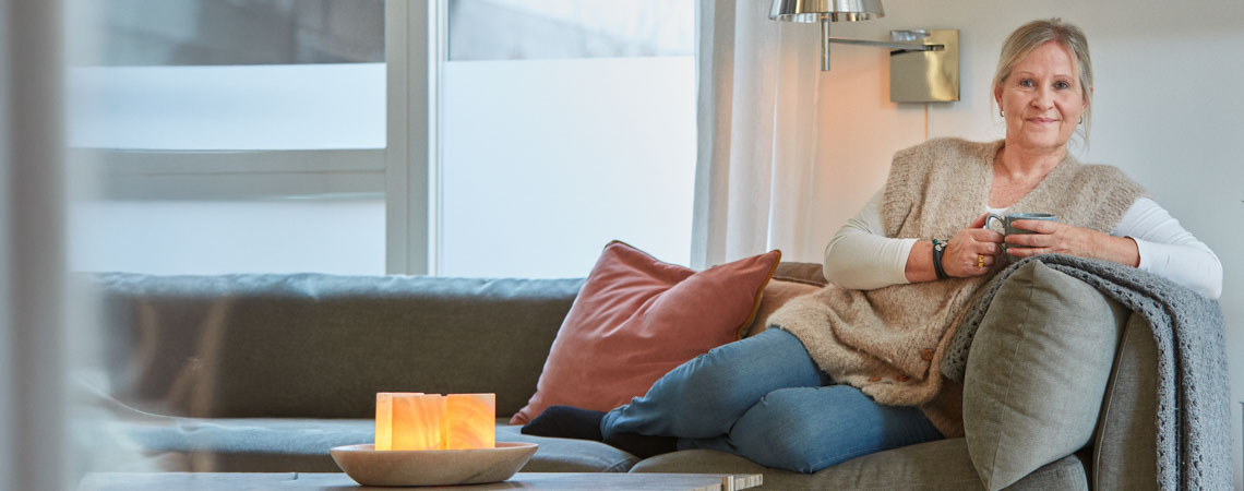 Ældre kvinde sidder i sofa