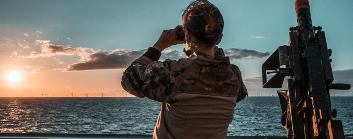 Soldat kigger over havet ved siden af en et skydevåben